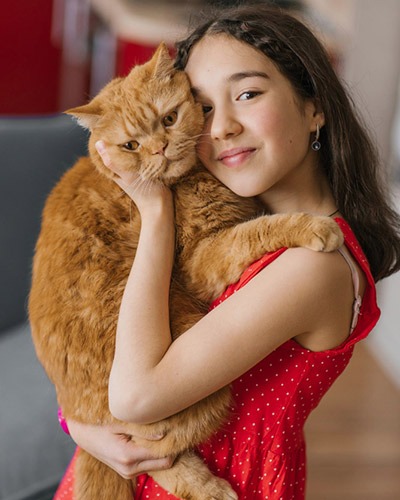 Pet owner holding her orange cat during a veterinary care visit in Mesa, AZ